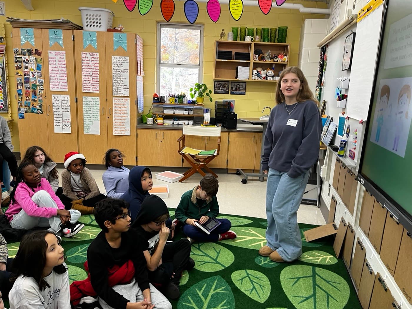A mentor teaching a recycling lesson on a classroom smartboard